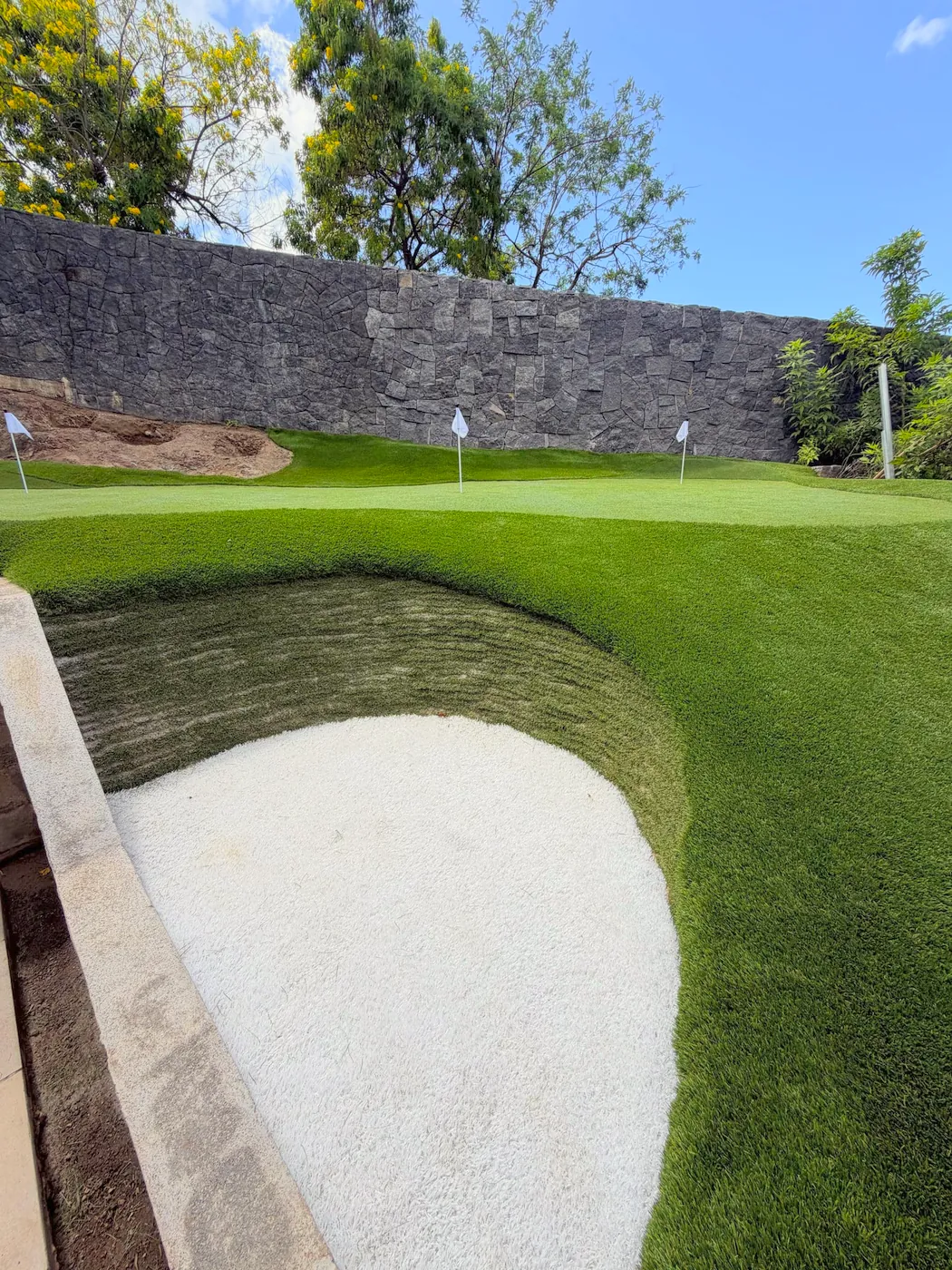 Turf cut cleanly around the lip of a sand bunker