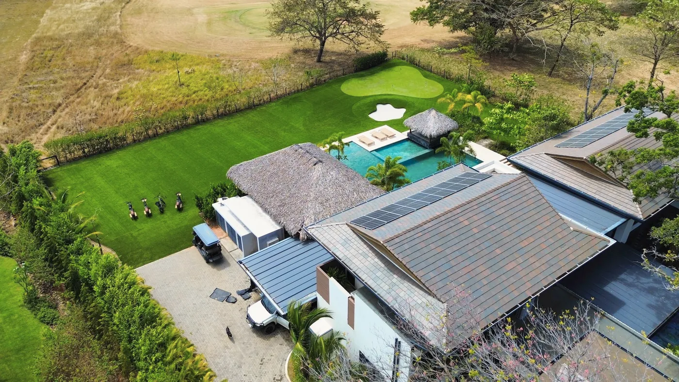 Drone view of a home with a pool and a wide synthetic lawn