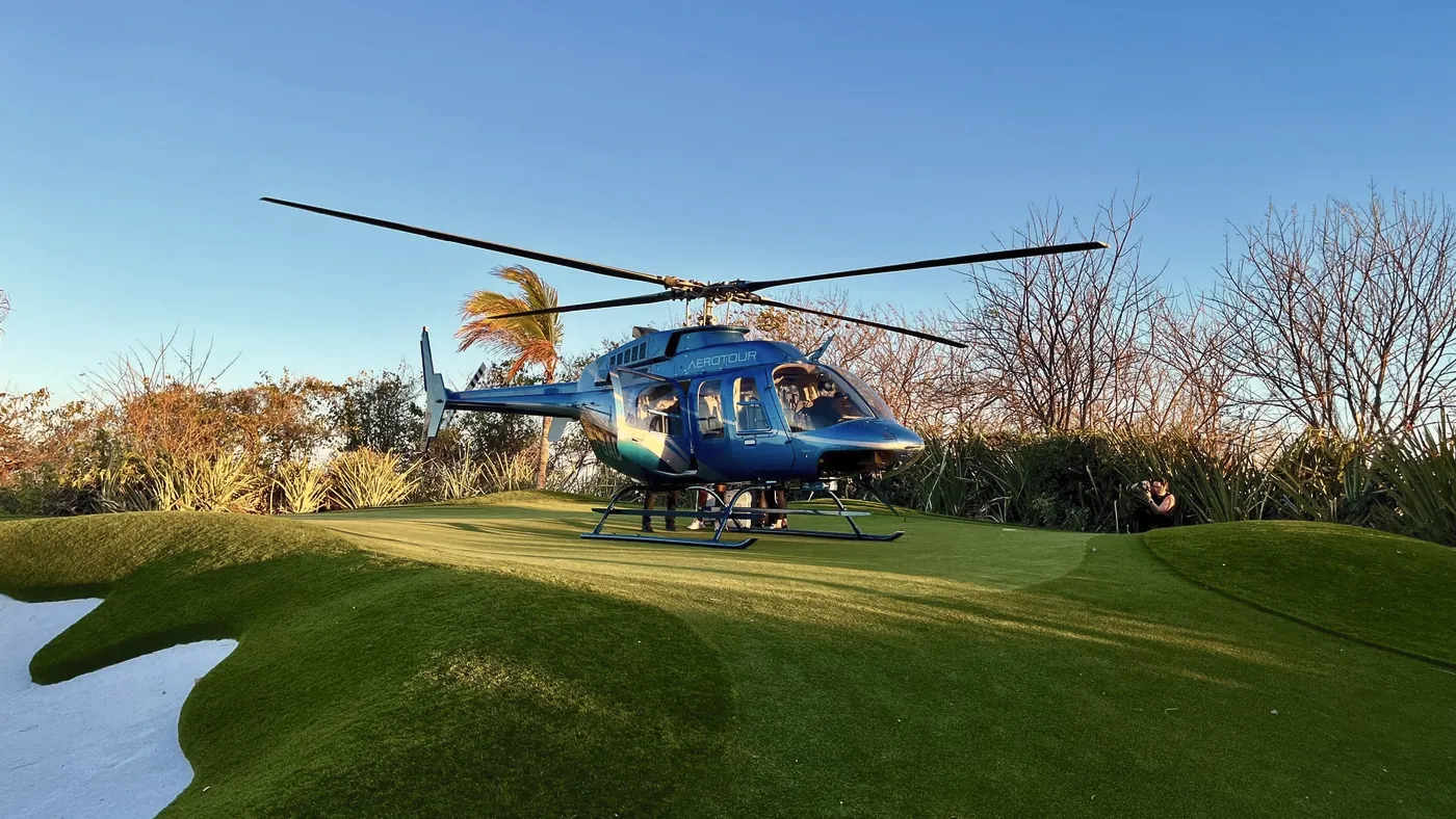 A tour helicopter parked on a contoured synthetic green