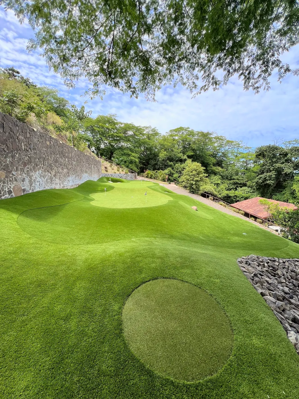 A putting green shaped into a hillside above the treetops