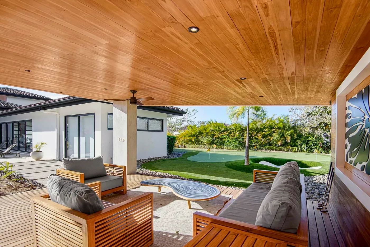 A shaded lounge looking out over a lawn and putting green