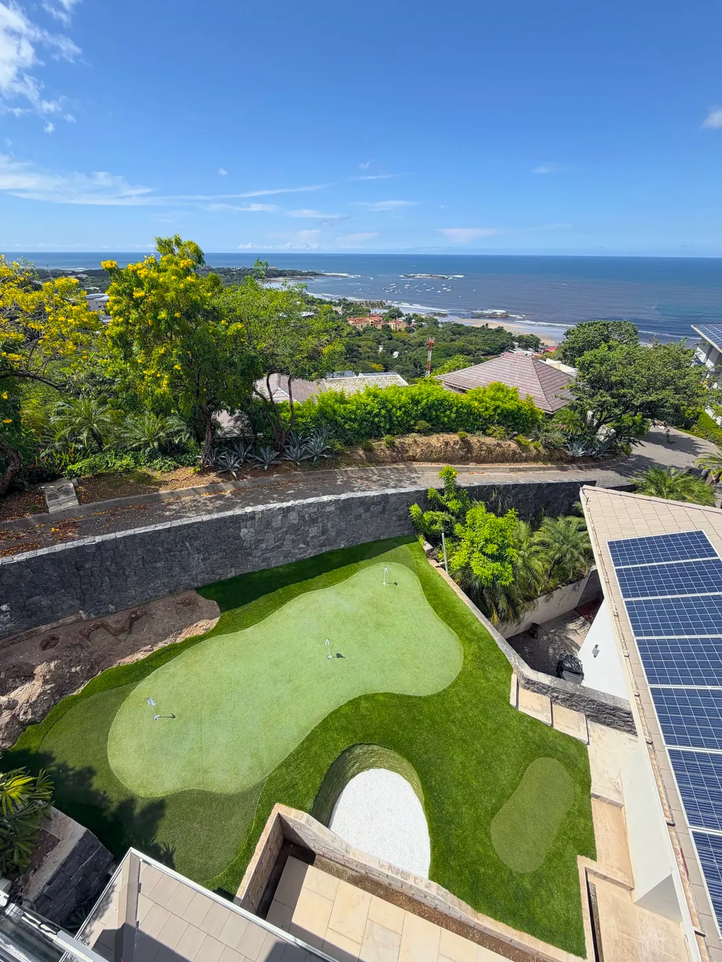 Putting green en un jardín rodeado de muros, con el mar al fondo