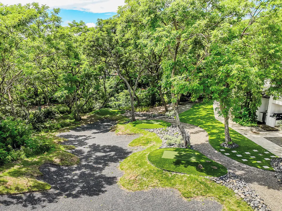 Large residential putting green blended with natural landscaping and rock gardens.