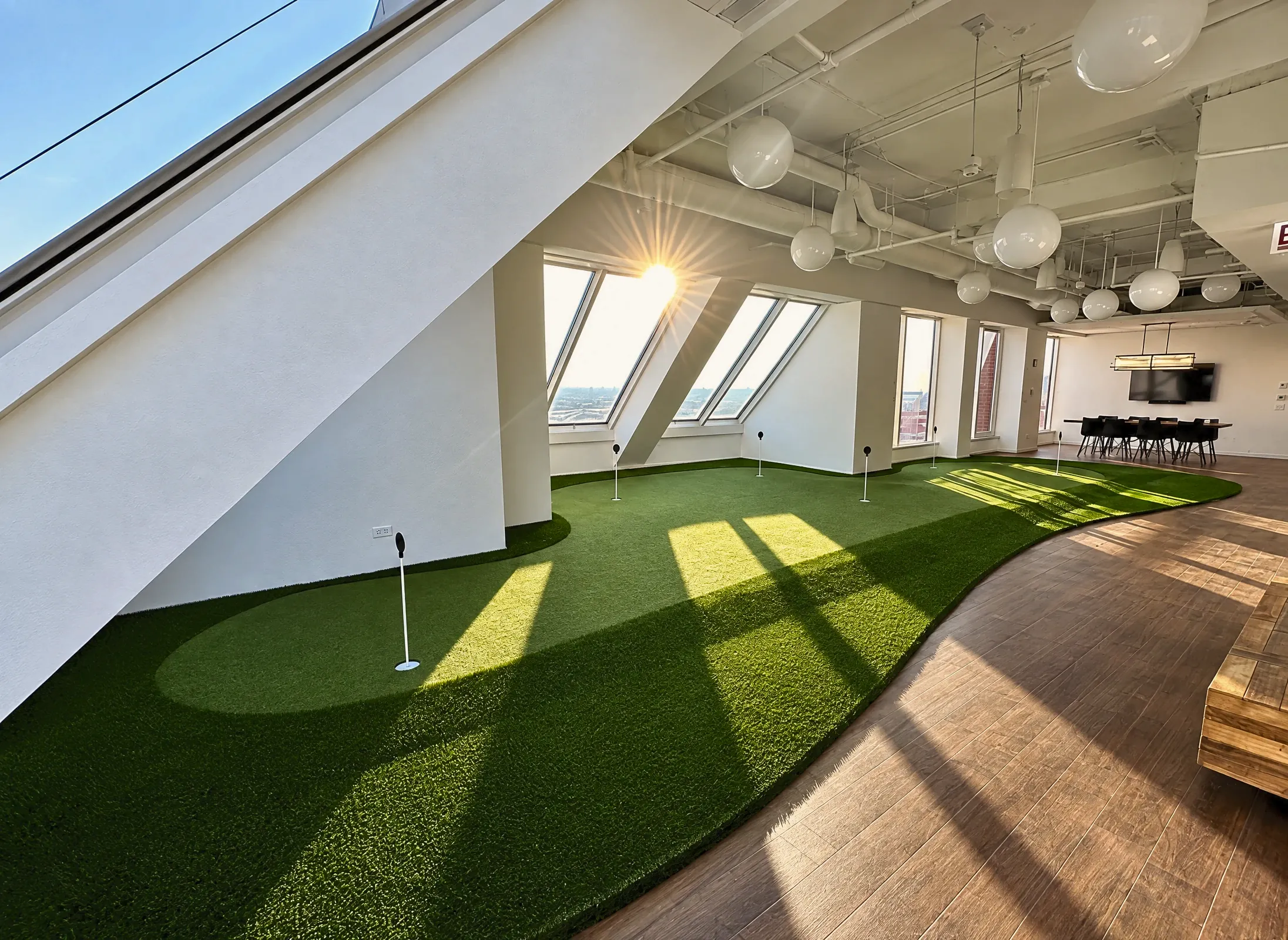 An indoor putting green running the length of a sunlit office floor
